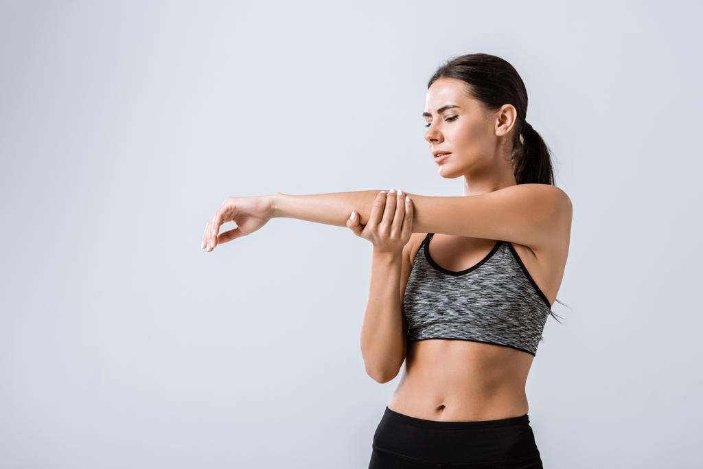 attractive sportswoman with arm pain isolated on grey - Photo, Image