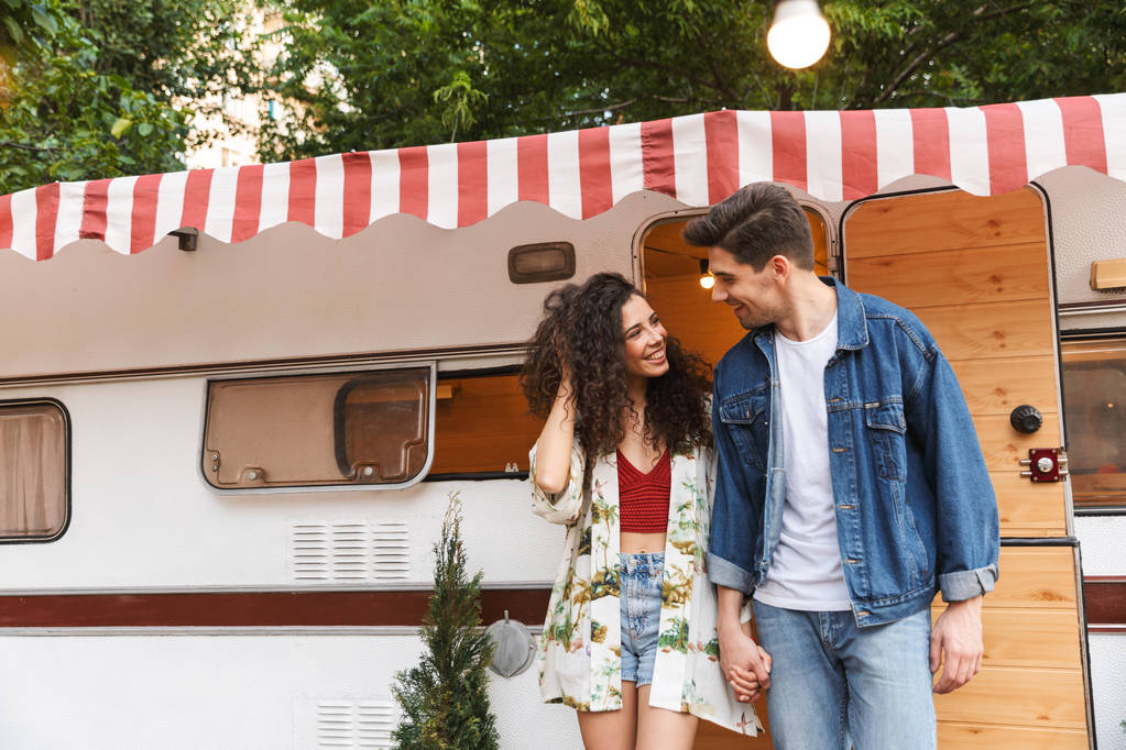 Jovem casal alegre falando enquanto está de pé no campvan
 - Foto, Imagem