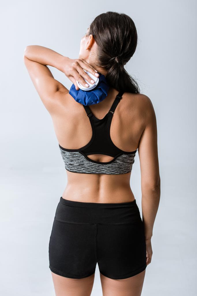 back view of sportswoman using ice for neck isolated on grey - Photo, Image