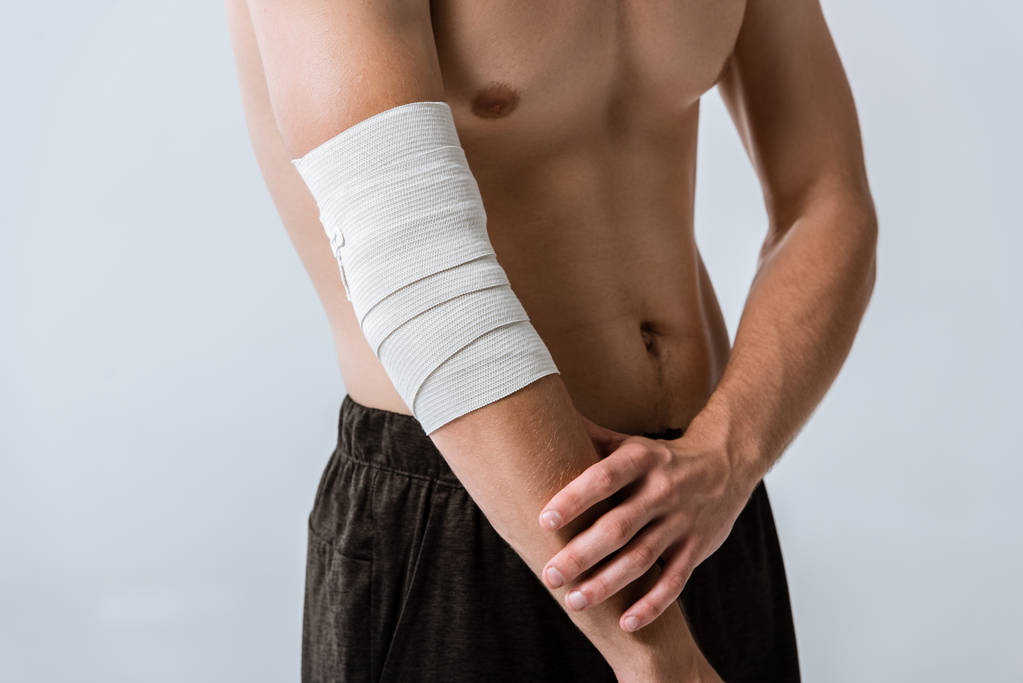 vue partielle du sportif torse nu avec bandage élastique sur le coude isolé sur gris
 - Photo, image