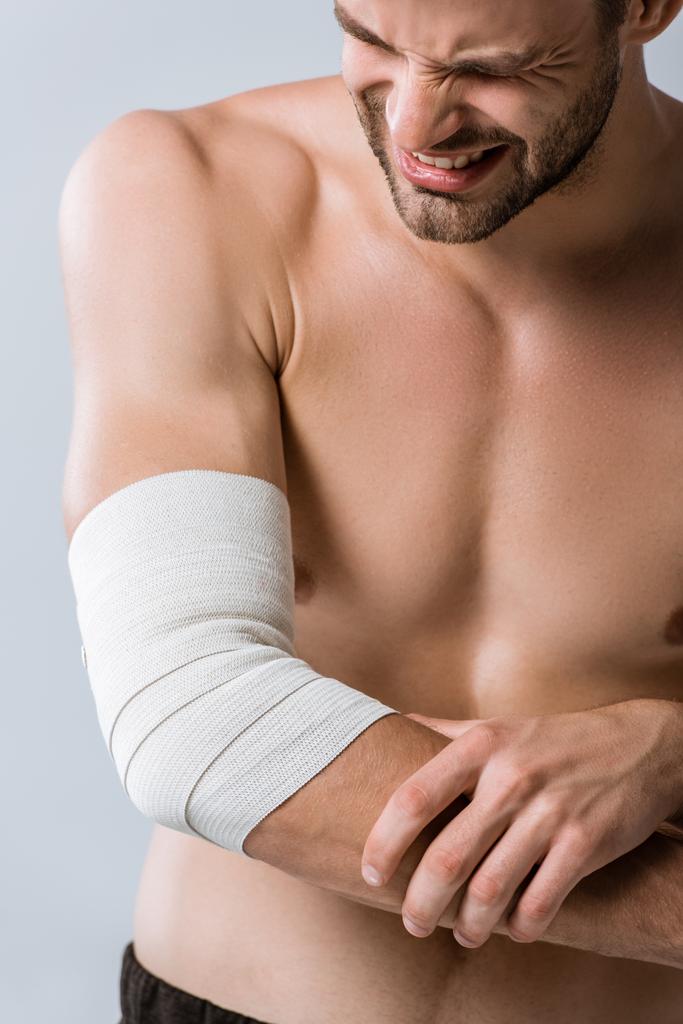 partial view of shirtless sportsman with elastic bandage on elbow isolated on grey - Photo, Image