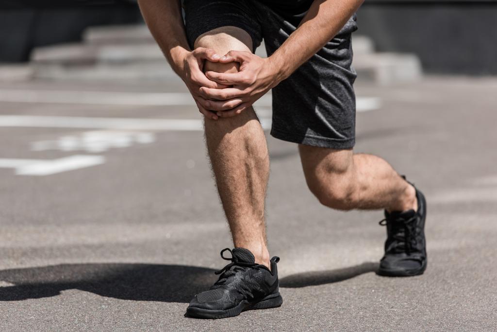 vista parcial del deportista con dolor de rodilla en la calle
 - Foto, imagen