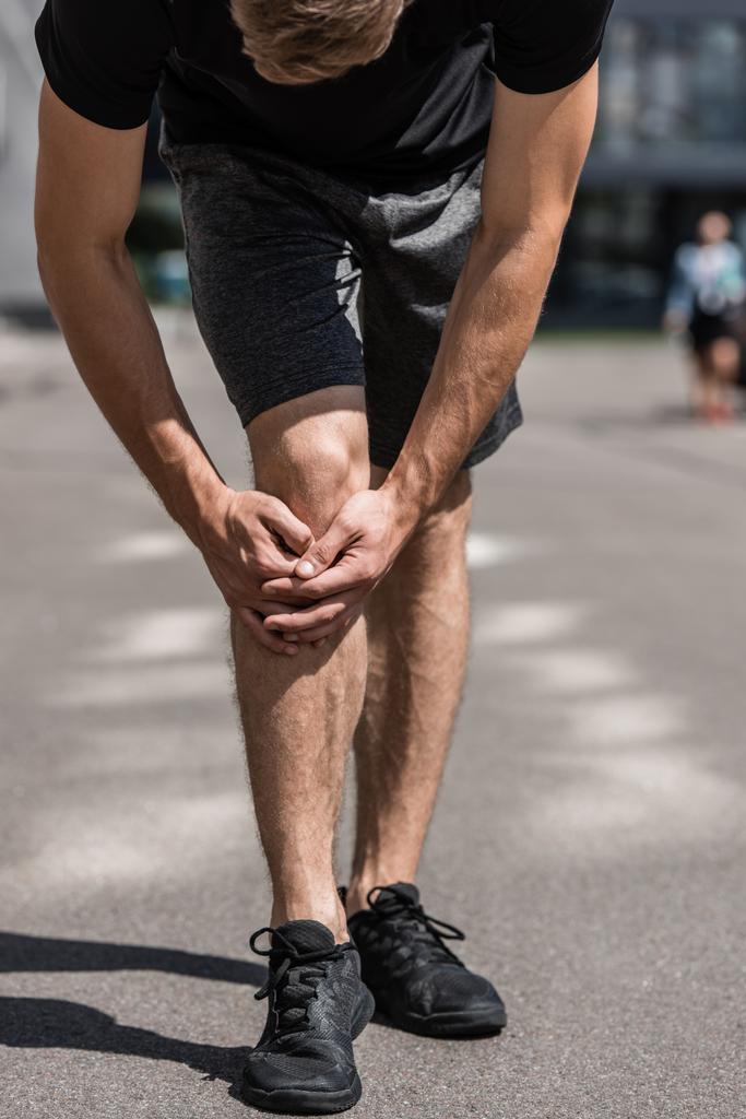 частичный взгляд спортсмена с болью в колене на улице
 - Фото, изображение