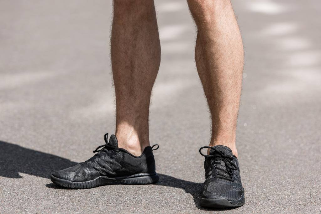 περικομμένη θέα του αθλητή σε μαύρα αθλητικά παπούτσια στο δρόμο - Φωτογραφία, εικόνα