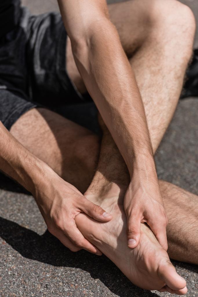 частичный вид босоногого спортсмена с болью в ногах на улице
 - Фото, изображение