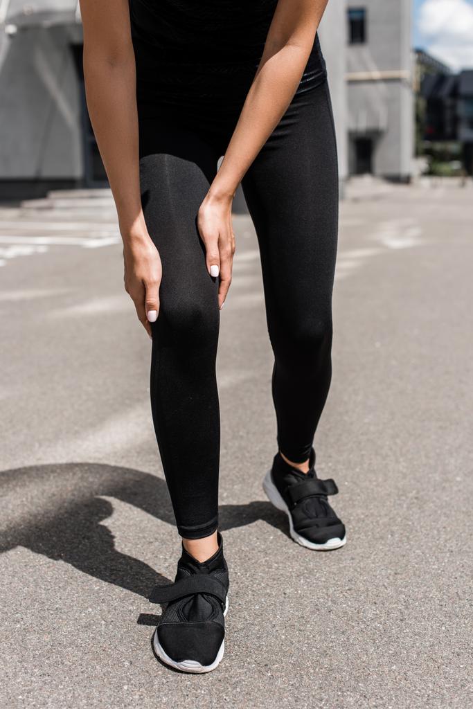 sokakta diz ağrısı ile siyah spor ayakkabı sporcu kırpılmış görünümü - Fotoğraf, Görsel