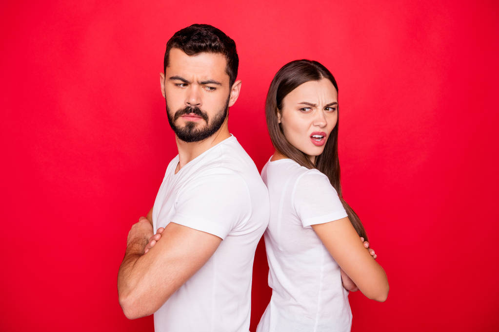 Foto van triest boos ongelukkig trendy stijlvolle blanke mensen dragen t-shirts offensief kijken naar elkaar terwijl geïsoleerd met rode achtergrond - Foto, afbeelding