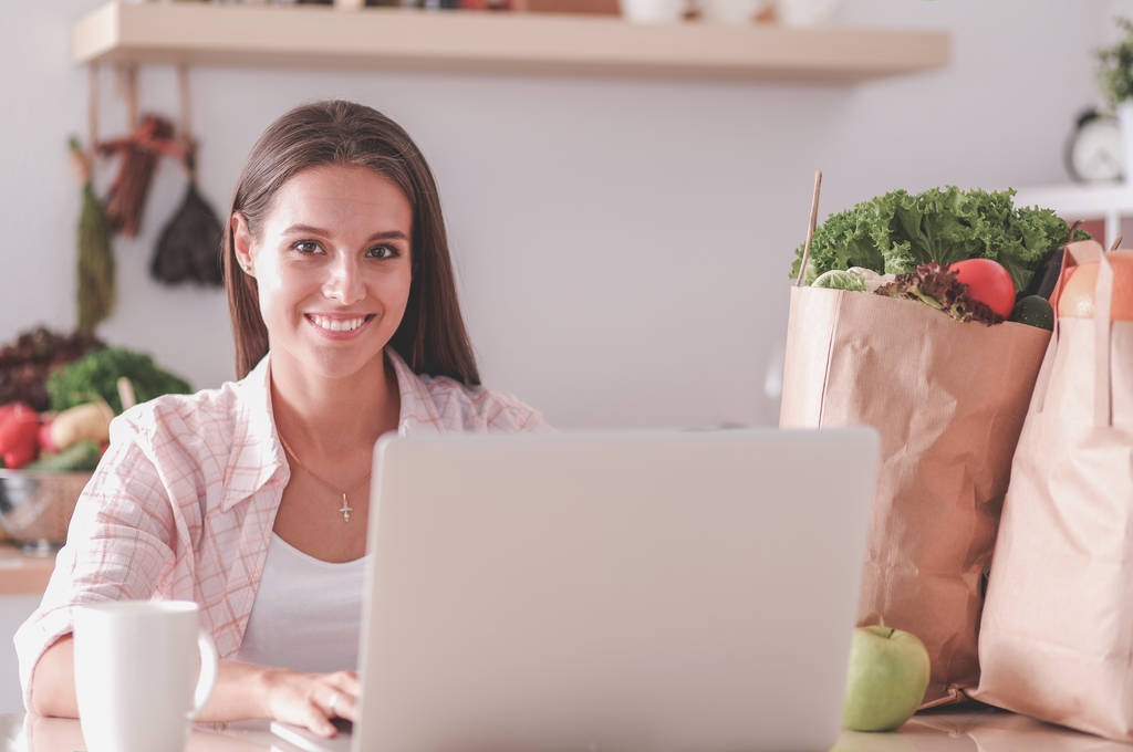 Усміхнена жінка в Інтернеті купує за допомогою планшета та кредитної картки на кухні. Усміхнена жінка
 - Фото, зображення