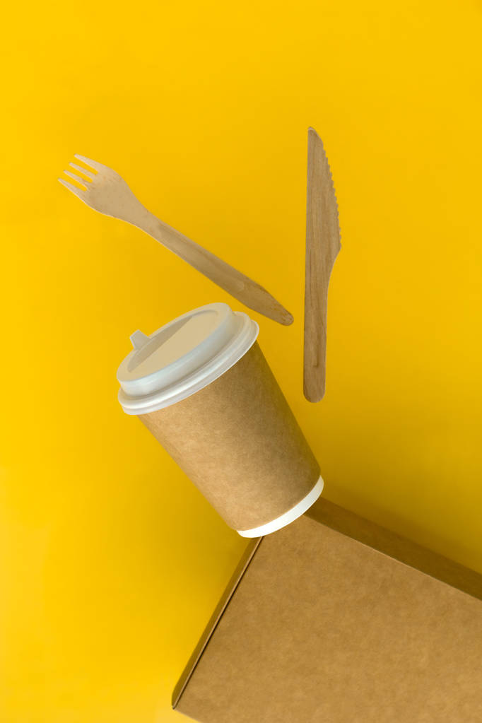 ympäristöystävällinen ruoka pakkaus asettaa kertakäyttöinen kuppi, laatikko, lusikka ja haarukka lentää keltaisella taustalla
 - Valokuva, kuva