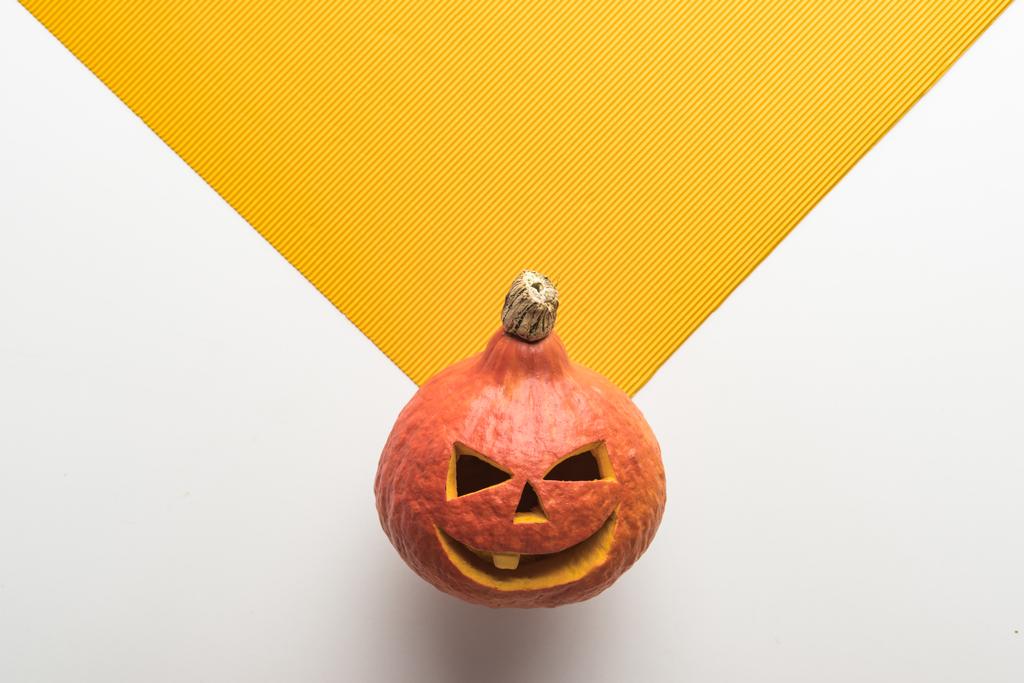 Draufsicht auf Halloween-Kürbis auf weißem und orangefarbenem Hintergrund - Foto, Bild