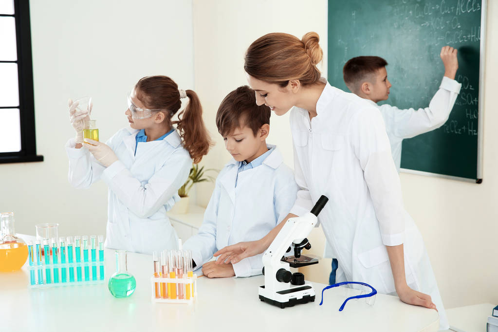 Opettaja ja oppilaat kemian tunnilla luokkahuoneessa
 - Valokuva, kuva