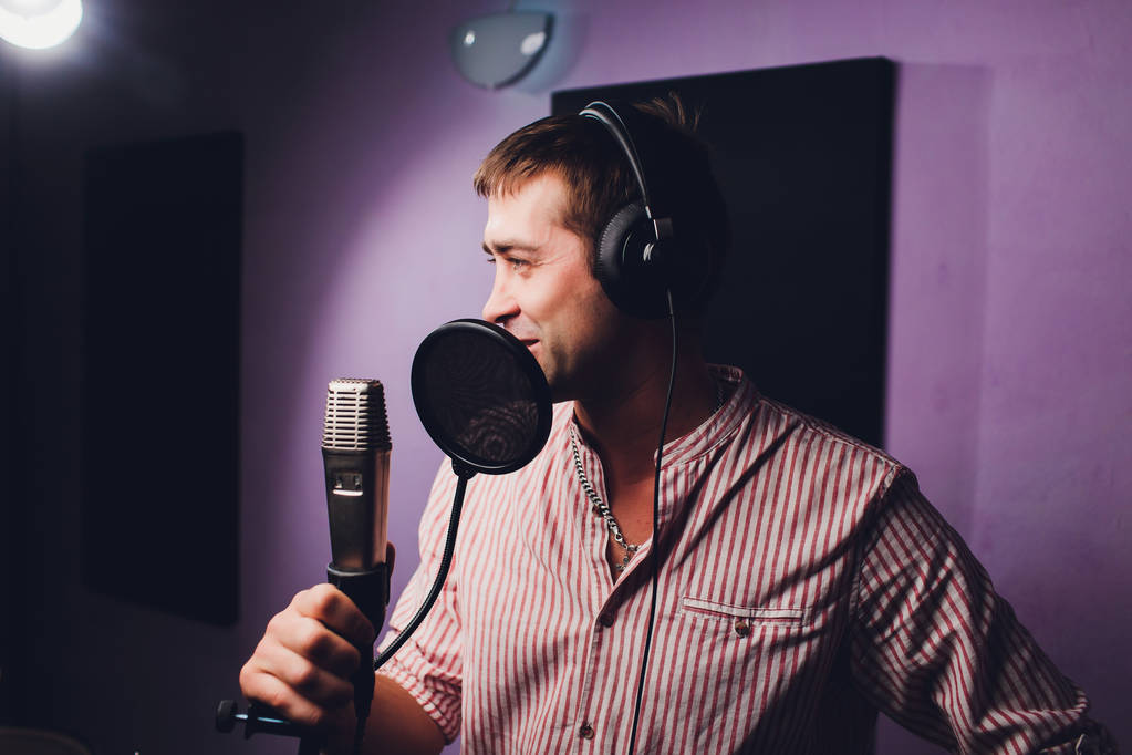 zene, show business, emberek és hang koncepció - férfi énekes fejhallgató és mikrofon énekelt dal hang stúdió. - Fotó, kép