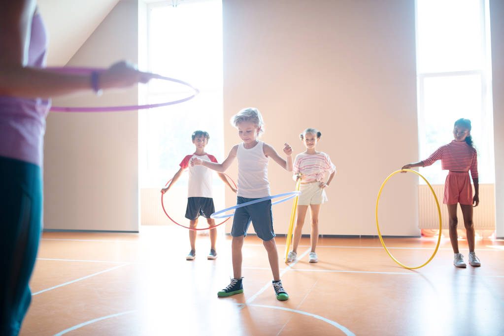 Boys and girls rolling hula-hoops at physical training - Photo, Image