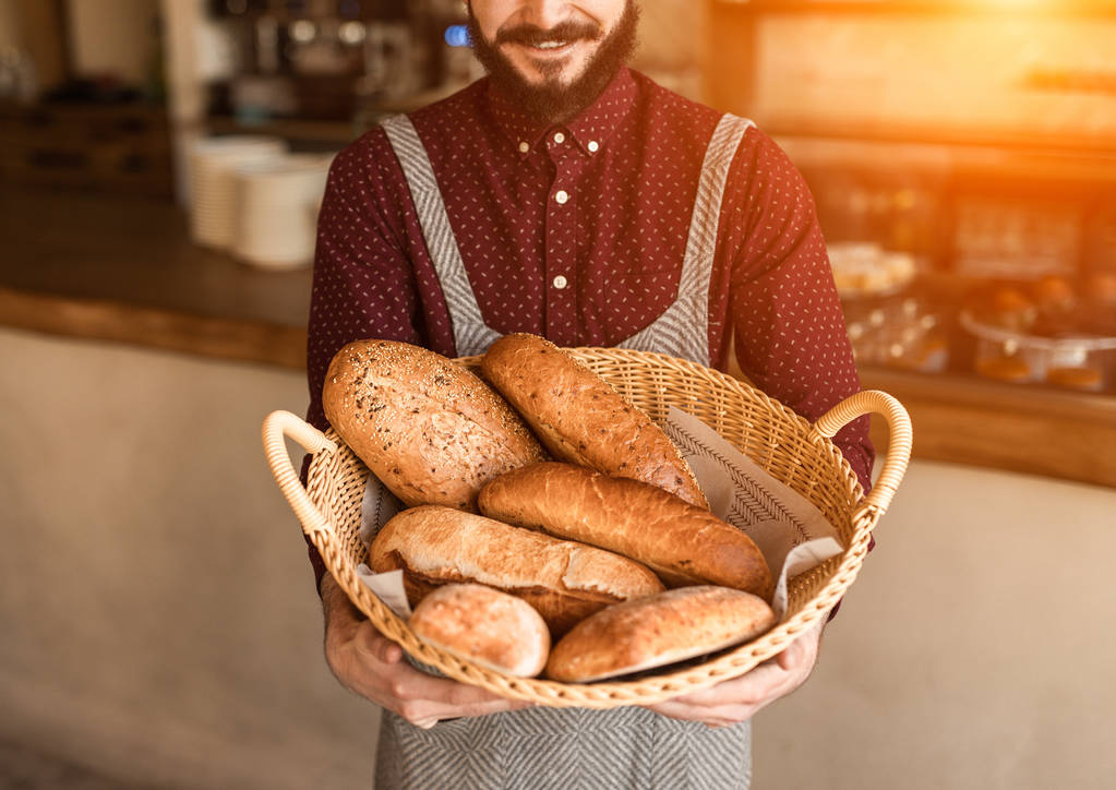Crop baker with basket of bread - Photo, Image