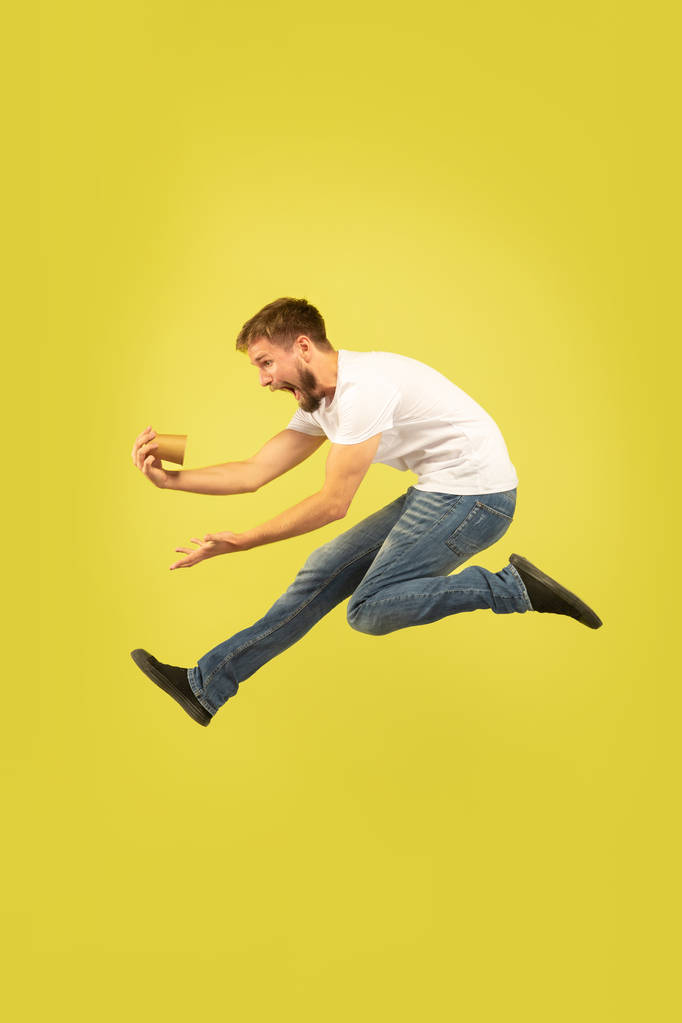 Ganzkörperporträt eines glücklichen springenden Mannes auf gelbem Hintergrund - Foto, Bild