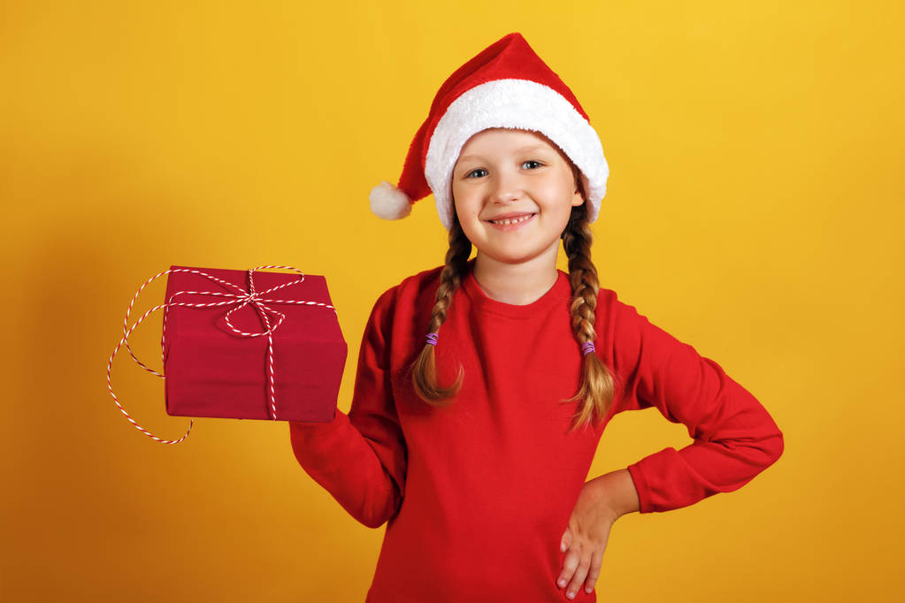 Porträt eines glücklichen kleinen Mädchens mit einem Weihnachtsgeschenk. das Kind hält eine Schachtel mit einem Geschenk - Foto, Bild