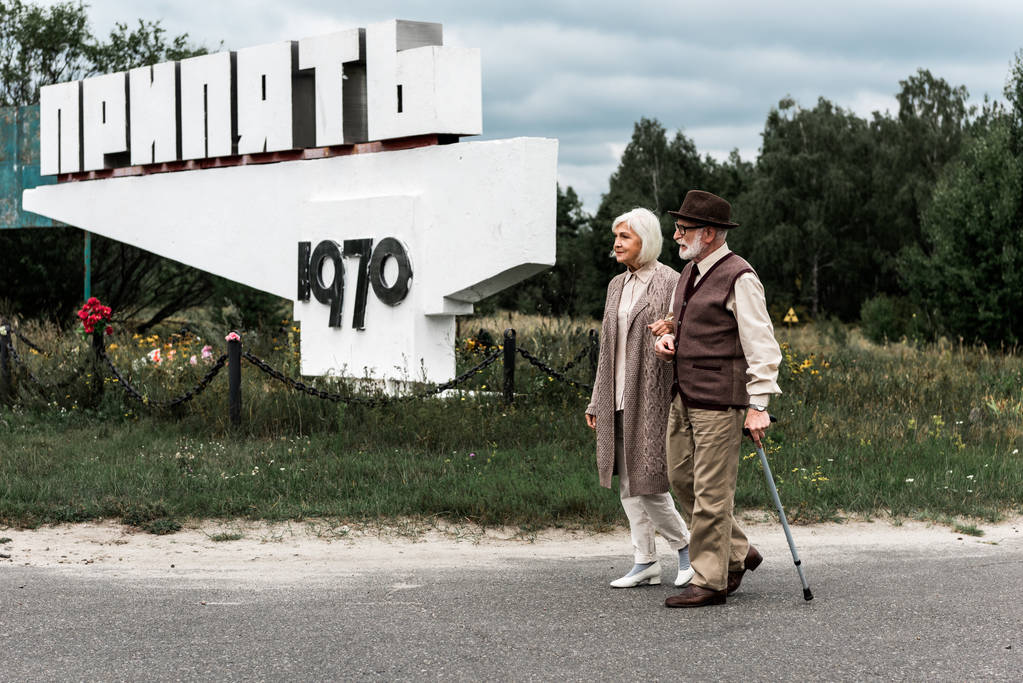 pripjat, ukraine - 15. August 2019: Rentner und Frau gehen in der Nähe von Denkmal mit Pripjat-Buchstaben - Foto, Bild