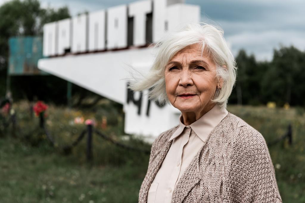 Pripjaty, Ukrajna-augusztus 15, 2019: Senior nő állandó közelében emlékmű a Pripjaty betűk - Fotó, kép