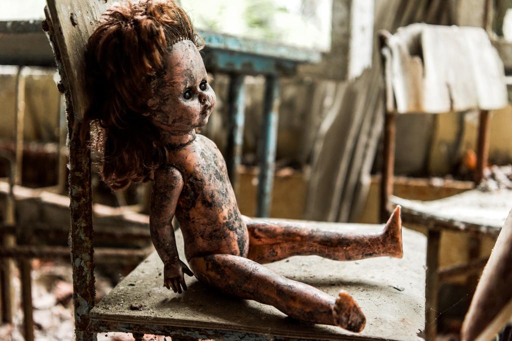 selective focus of dirty and burnt baby doll on wooden chair in school  - Photo, Image