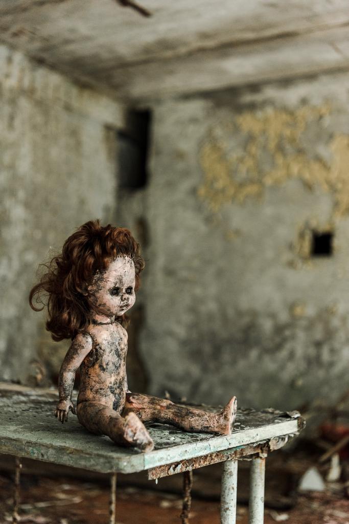 汚れた机の上に放棄され、燃やされた赤ちゃんの人形  - 写真・画像