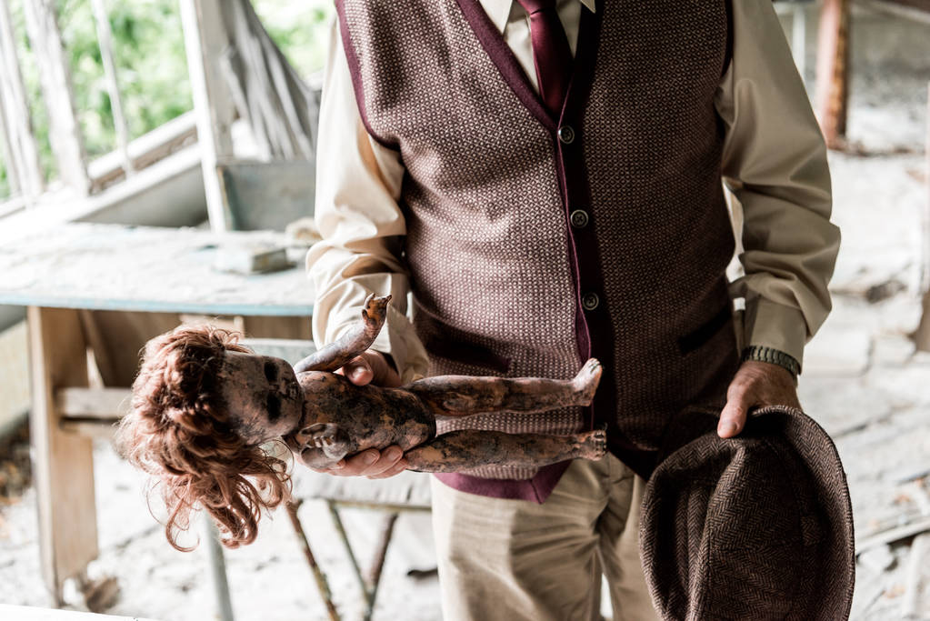 обрезанный вид пожилого человека, держащего шляпу и грязную куклу в классе
  - Фото, изображение