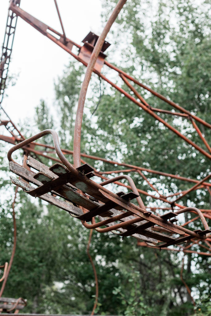 Pripyat, Ukrayna - 15 Ağustos 2019: Çernobil'deki yeşil eğlence parkında kırmızı metalik atlıkarıncanın seçici odağı  - Fotoğraf, Görsel