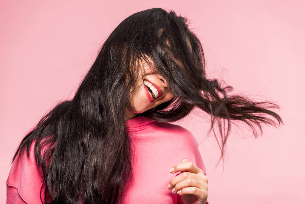 mulher em pulôver rosa sorrindo e brincando com o cabelo isolado em rosa
  - Foto, Imagem