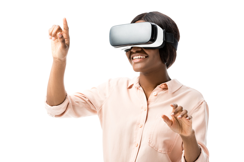 Afrikaans amerikaanse vrouw in shirt met virtual reality headset wijzend met vinger geïsoleerd op wit  - Foto, afbeelding