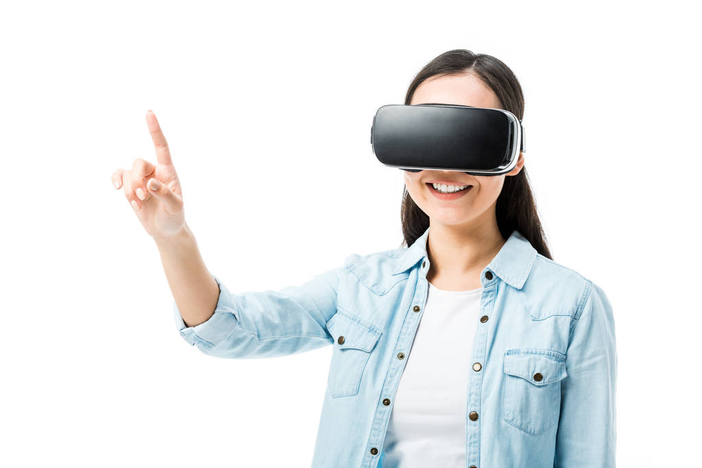 donna sorridente in camicia di jeans con auricolare realtà virtuale che punta con dito isolato su bianco
  - Foto, immagini