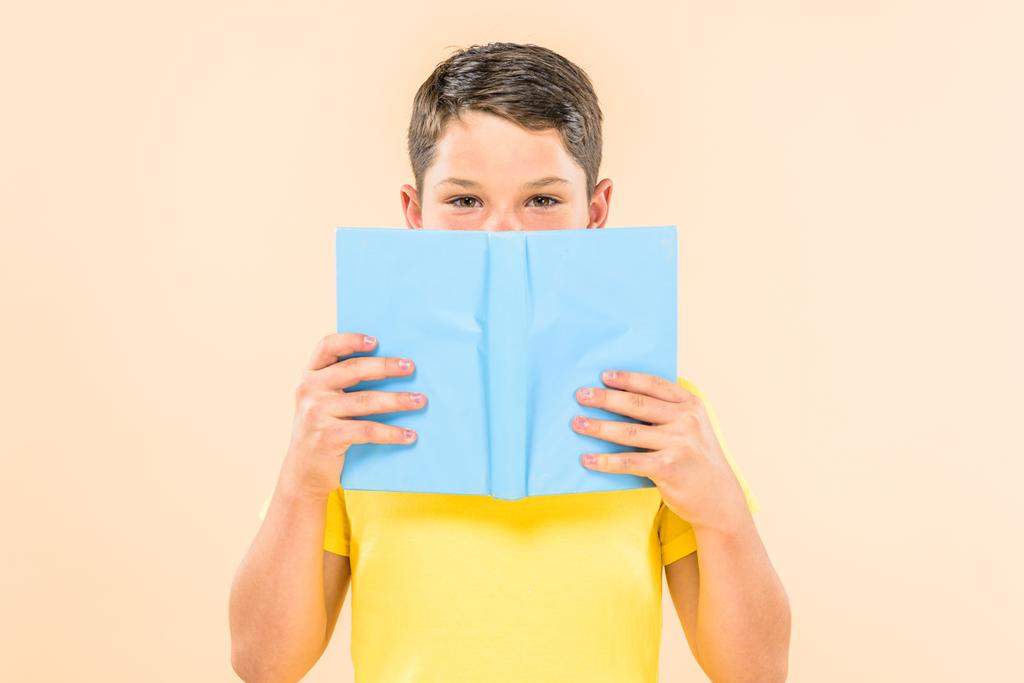 μπροστινή όψη του αγοριού με κίτρινο t-shirt Holding βιβλίο απομονώνεται σε ροζ - Φωτογραφία, εικόνα