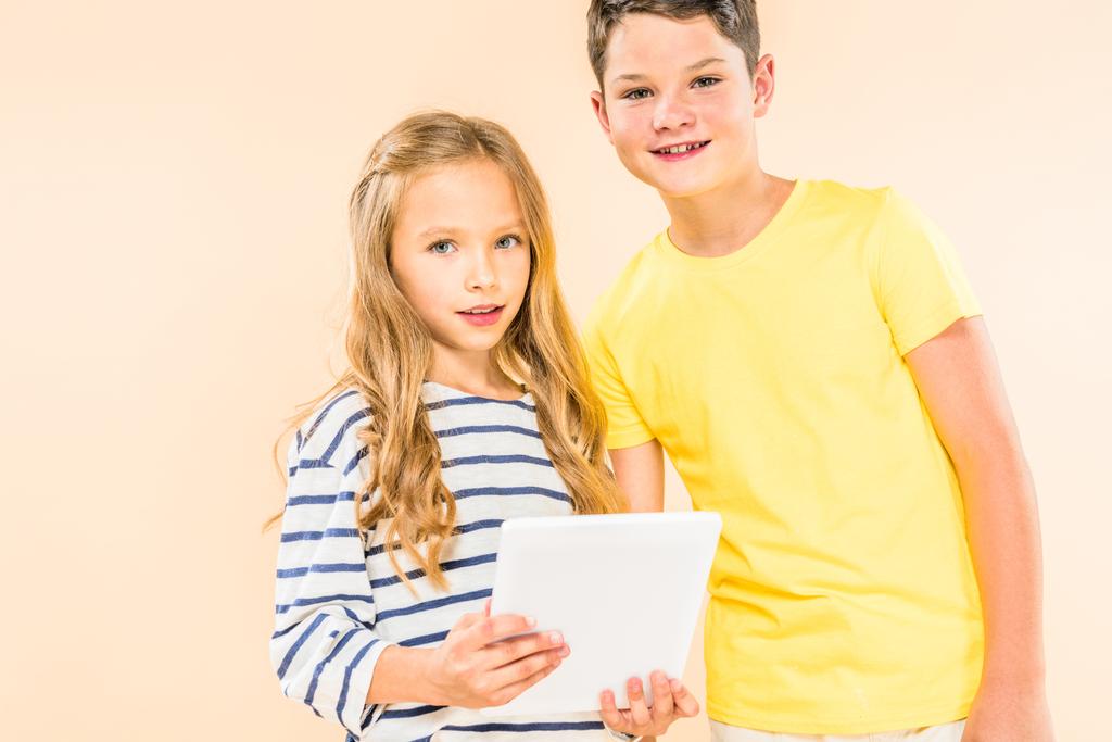 дві усміхнені діти використовують цифровий планшет ізольовані на рожевому
 - Фото, зображення