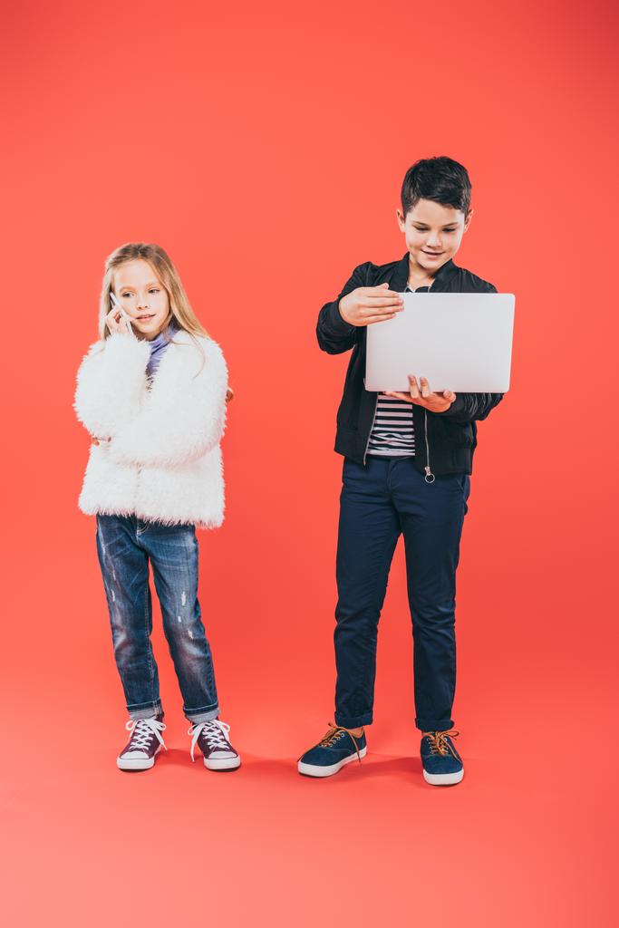 full length view of kids with smartphone and laptop on red - Photo, Image