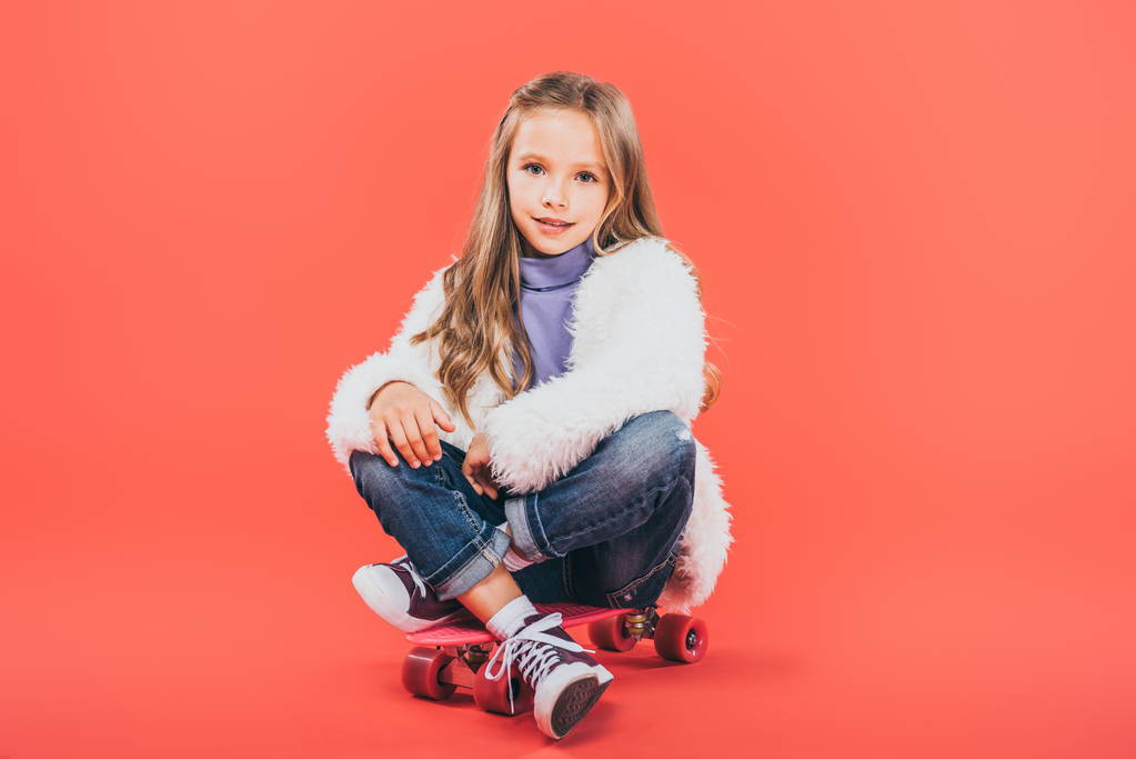 kid in autumn outfit sitting on skateboard on red - Photo, Image