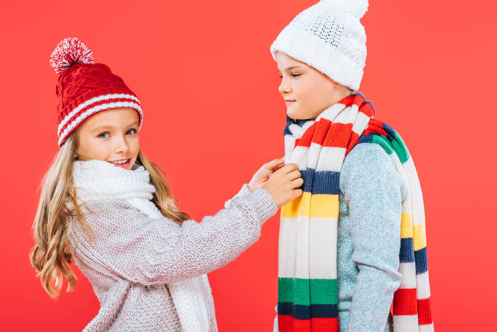two kids in winter outfits isolated on red - Photo, Image