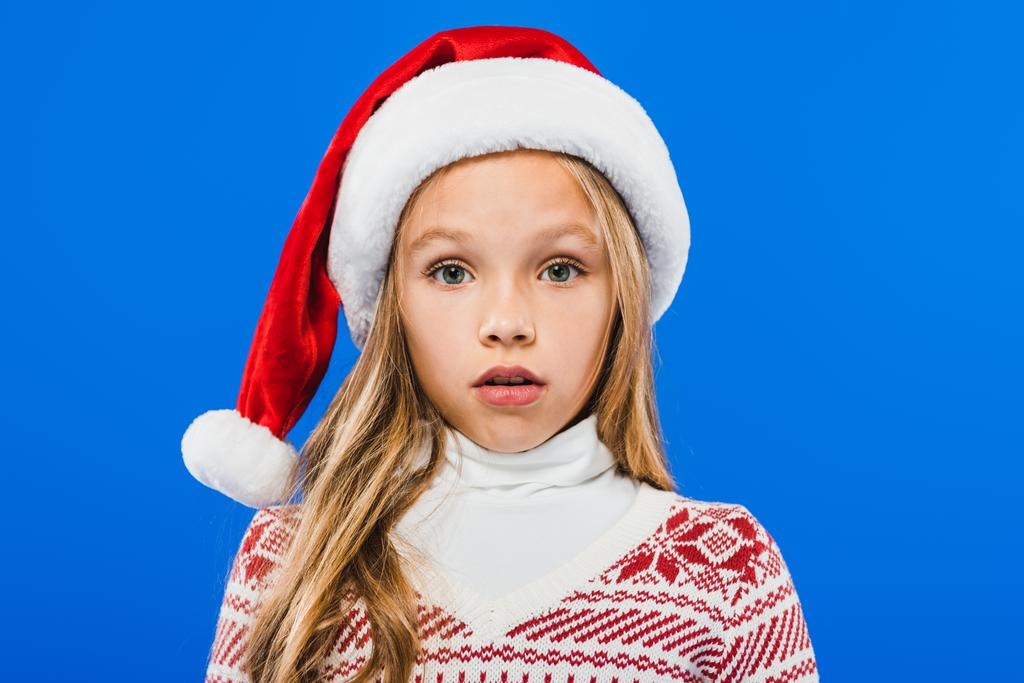 front view of surprised kid in santa hat isolated on blue - Photo, Image