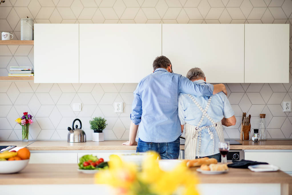 Vista posteriore del figlio adulto e padre anziano in casa, cucina
. - Foto, immagini