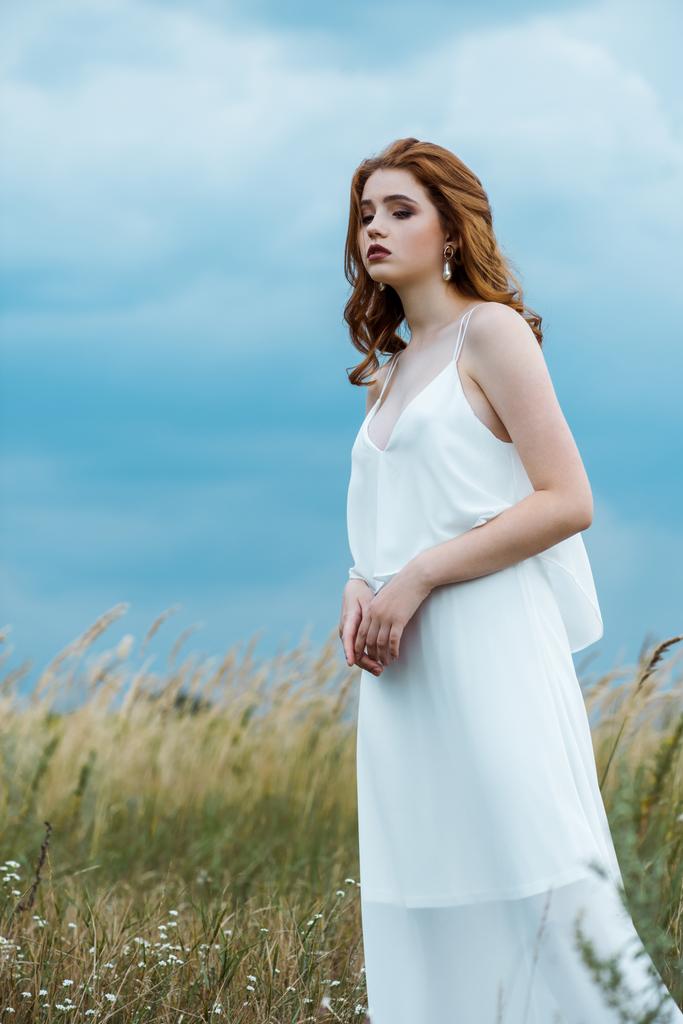 расстроенная и красивая молодая женщина в платье, стоящая в поле
  - Фото, изображение