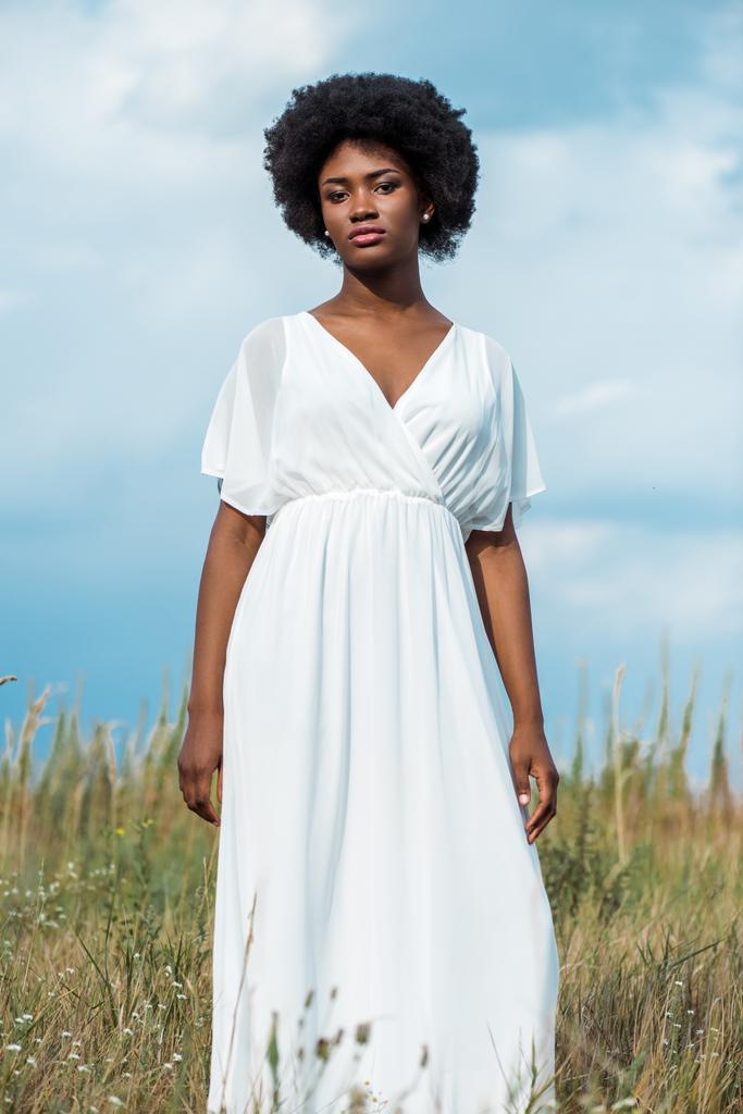 attrayant et bouclé afro-américaine femme en robe blanche contre le ciel bleu
  - Photo, image
