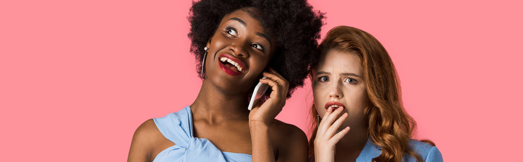 colpo panoramico di felice donna africana americana che parla su smartphone vicino preoccupato rossa ragazza isolata su rosa
  - Foto, immagini