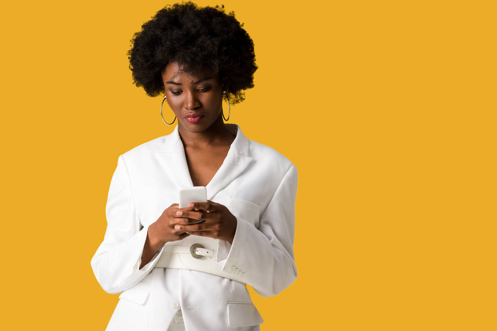 krásná složená africká americká žena používající smartphone izolovaný na oranžový  - Fotografie, Obrázek