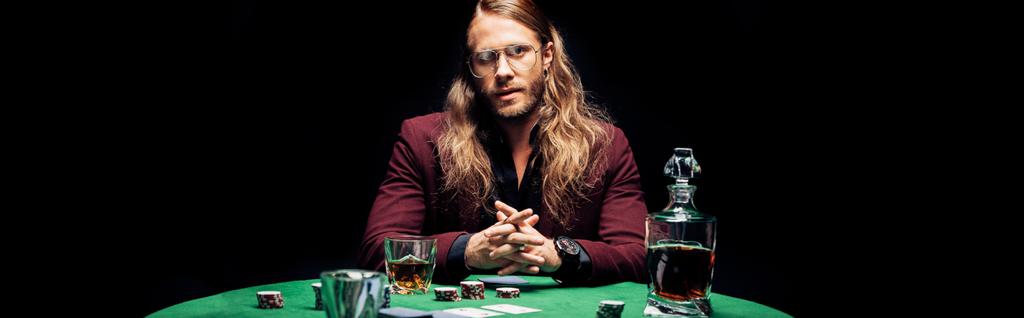 panoramic shot of bearded man in eye glasses near playing cards isolated on black  - Photo, Image