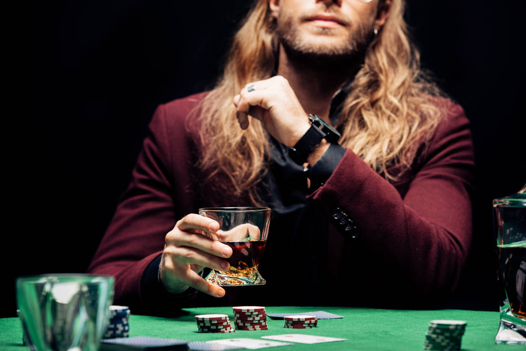 abgeschnittene Ansicht eines Mannes mit Glas mit Whiskey in der Nähe von Spielkarten isoliert auf schwarz  - Foto, Bild
