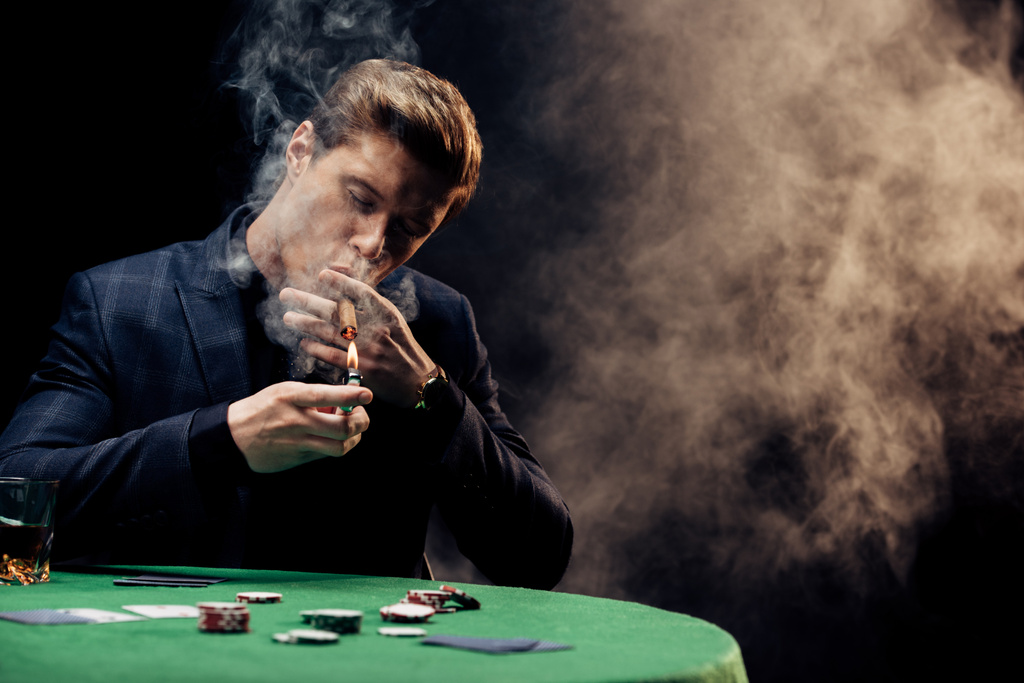 煙で黒い喫煙しながらライターを保持するハンサムな男の選択的な焦点  - 写真・画像