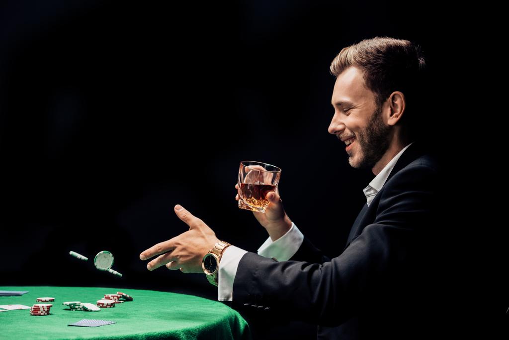 ευτυχισμένος άνθρωπος ρίχνοντας σε αέρα μάρκες πόκερ απομονωθεί σε μαύρο  - Φωτογραφία, εικόνα