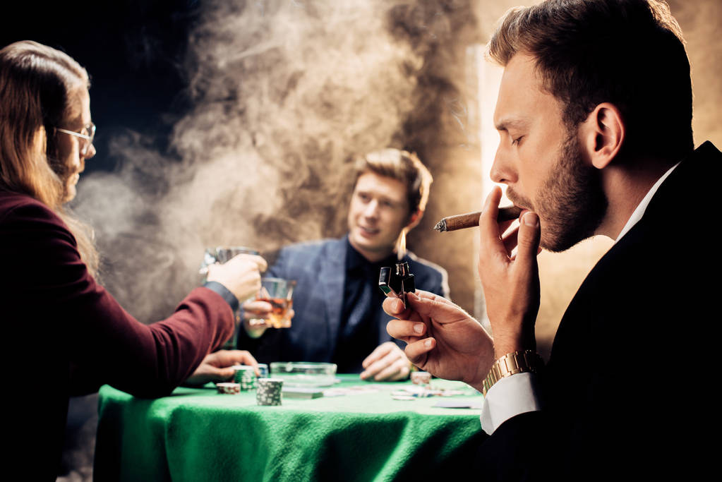 εκλεκτική εστίαση του όμορφου ανθρώπου που καπνίζει παίζοντας πόκερ στο μαύρο με καπνό  - Φωτογραφία, εικόνα
