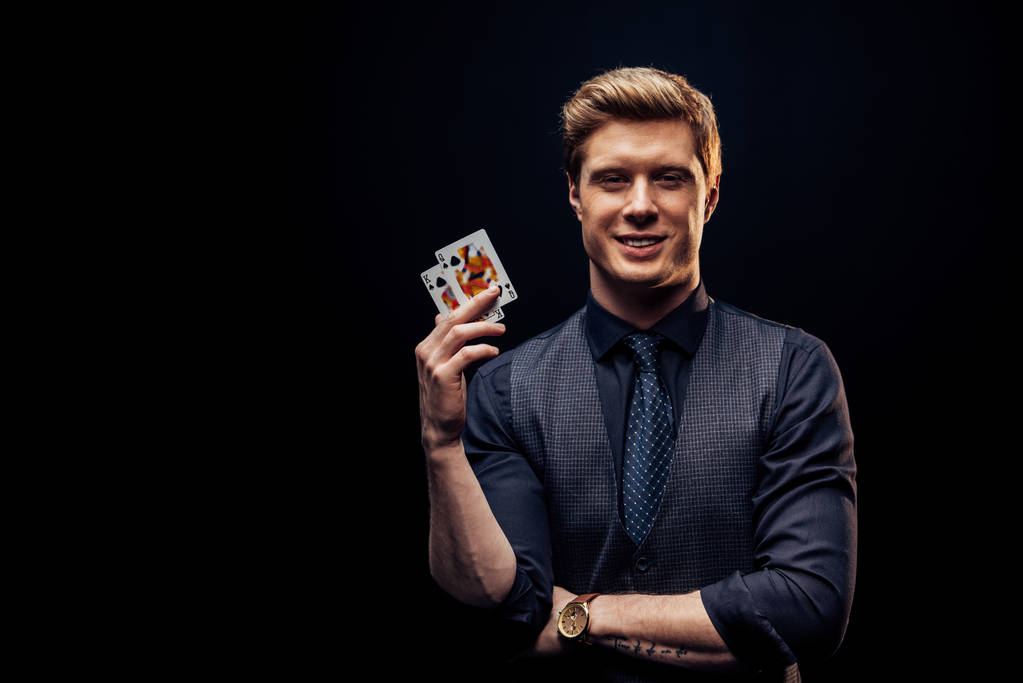 KYIV, UCRAINA - 20 AGOSTO 2019: uomo allegro che tiene le carte da gioco isolate sul nero
  - Foto, immagini