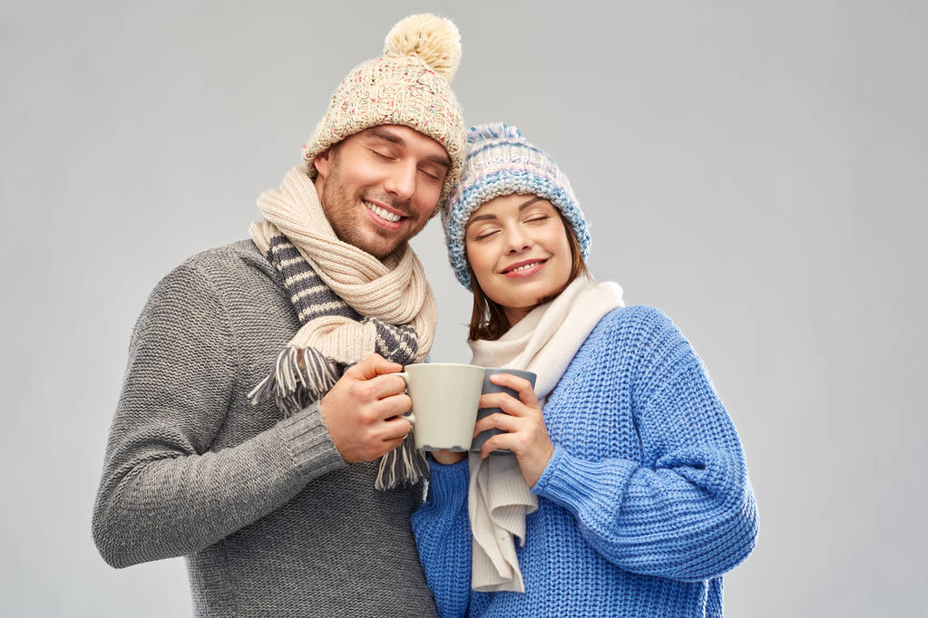 счастливая пара в зимней одежде с кружками - Фото, изображение