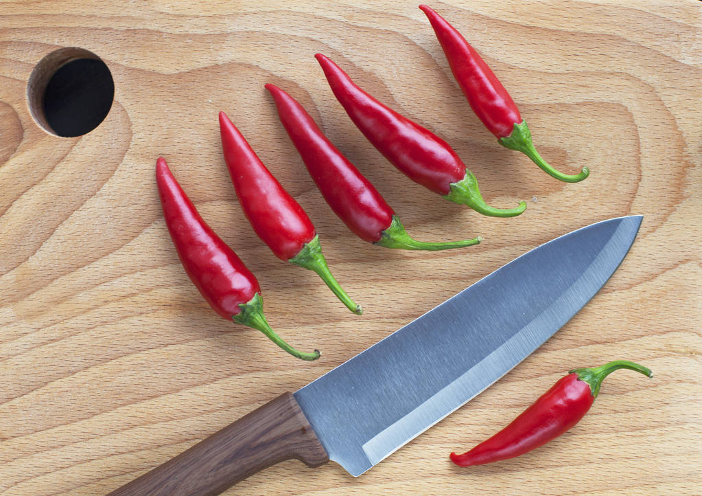 Cuchillo chef chile rojo sobre fondo de madera
 - Foto, Imagen