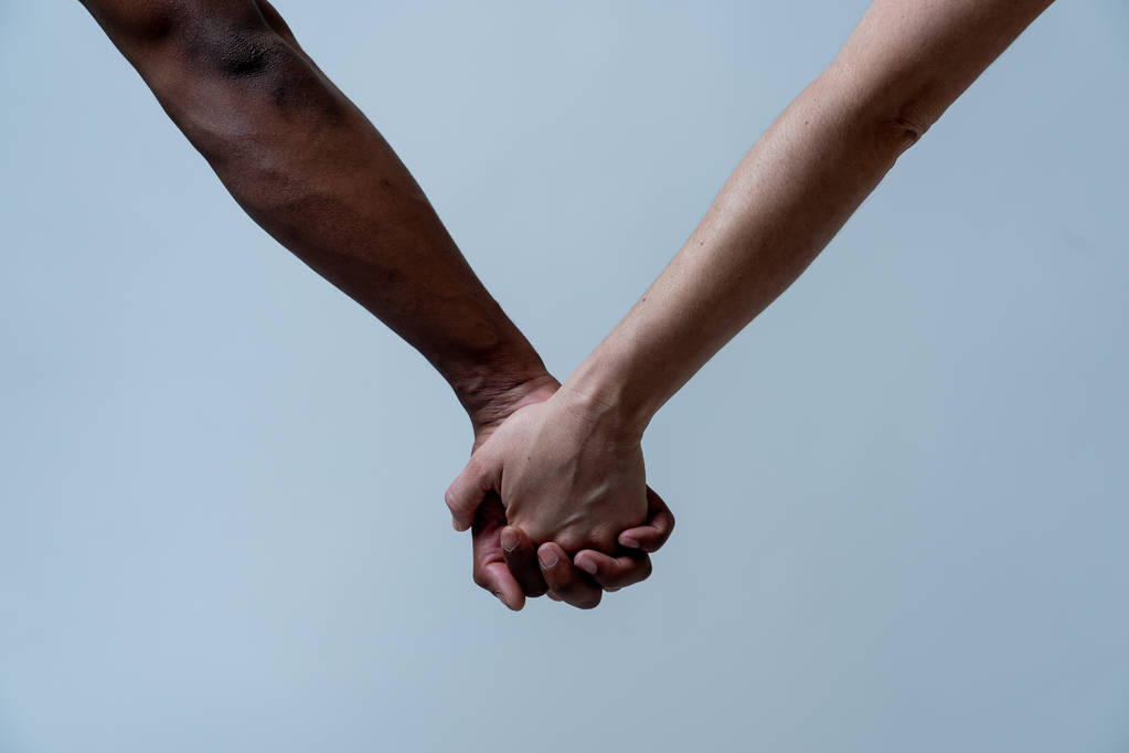 Pareja multirracial cogida de la mano en el amor. Brazos de piel blancos y negros que se mantienen unidos. Imagen conceptual de la unidad mundial amor interracial y comprensión en la tolerancia y la diversidad
. - Foto, imagen