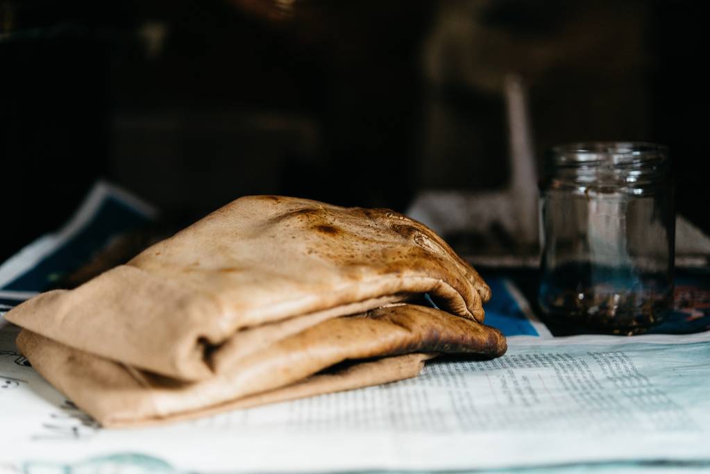Bulanık arka planlı bir kavanozun yanındaki gazetede lavaş ekmeğinin yakın çekimi - Fotoğraf, Görsel
